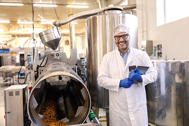 istock Food processing engineer smiling in factory with machine 2245890707