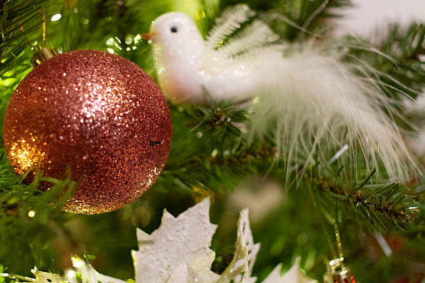 istock Red glitter bauble and white bird with feather tail on a lit Christmas tree. 2245901609
