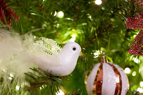 istock Red glitter poinsettia, white bird ornaments and baubles on pine tree branches. 2245902122