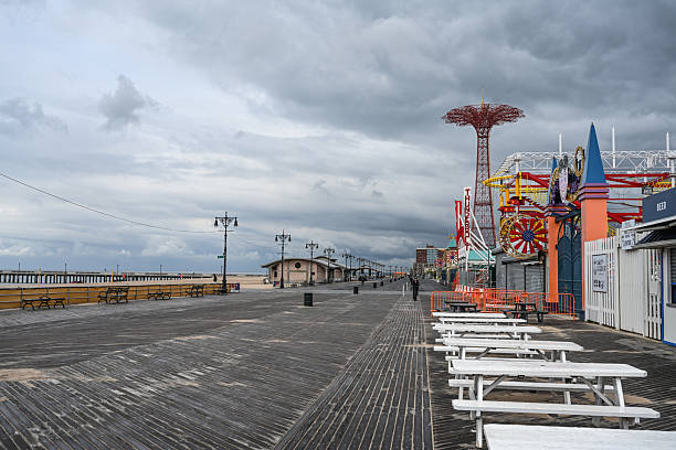 Wide aerial shot capturing Coney Island coastline with beachgoers and amusement park in background.