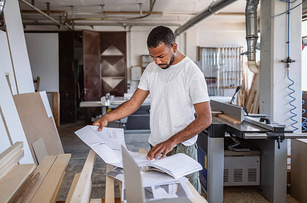 istock Focused Multiracial Male Carpenter Reviewing Blueprints in Bright Workshop 2245907710