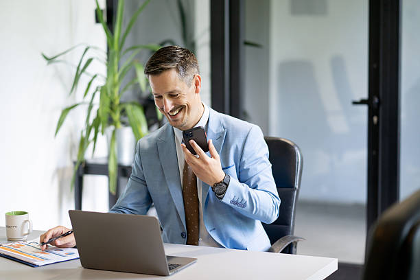 istock Businessman working on laptop and talking on mobile phone in office 2245907862