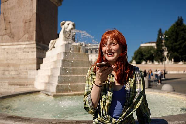Young red-haired woman texting or browsing on her phone at Piazza del Popolo in Rome.