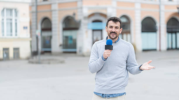 istock Enthusiastic Man Reporting in a City Square with a Microphone 2245909216