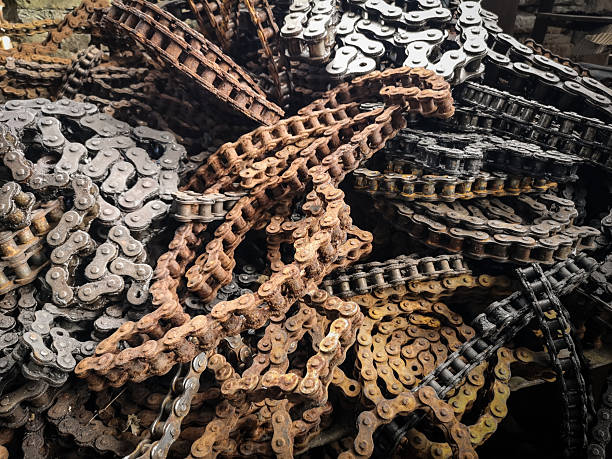 A dense pile of metal chains from bicycles and motorcycles, mixed in varied states of use  shiny, old, and rusted  forming a chaotic, almost organic pattern of iron and grease.