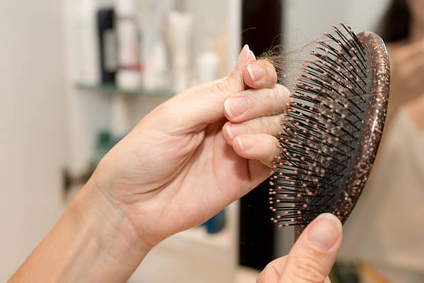 istock Woman Removing Hair from Brush After Combing 2245922122