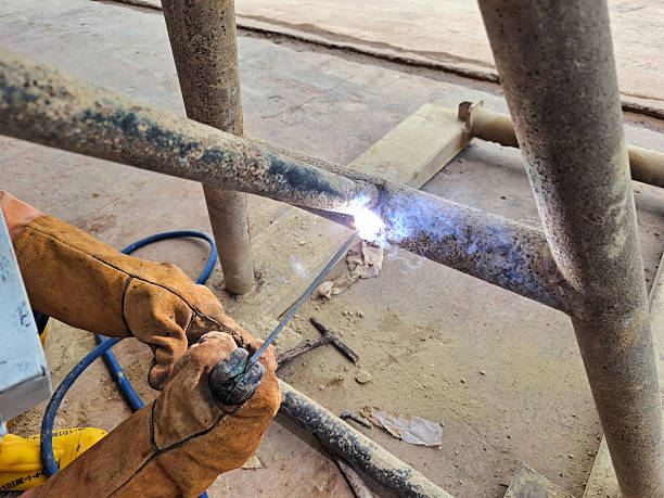 istock ​Close-up of industrial worker using arc welding to join rusty metal pipes on a construction site. Laborer wearing safety gloves. Heavy manual industrial metalworking job 2245922626