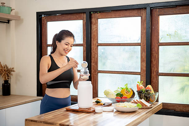 istock Asian woman using spoon scooping powder to jar making protein shake drink at kitchen cooking counter 2245923198
