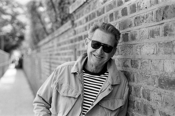 istock Senior man smiling and leaning against a brick wall in black and white 2245924890