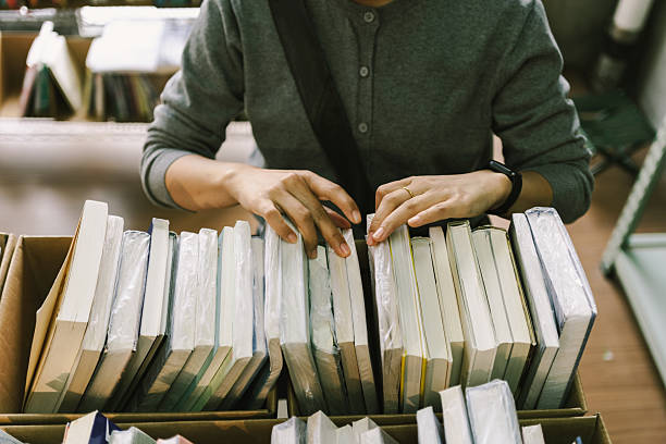 An Asian woman is in a second-hand bookstore, choosing second-hand books. It's a second-hand store