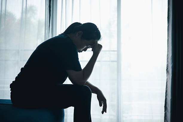 istock A stressed woman sitting alone on bed in dark room, holding her head down, symbolizing depression, anxiety, hopelessness, loneliness, mental health struggle, burnout and emotional pain. 2245926891