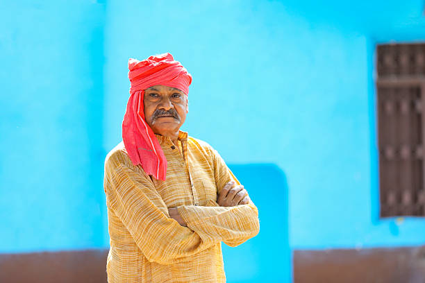 Old and senior indian farmer standing and giving happy expression