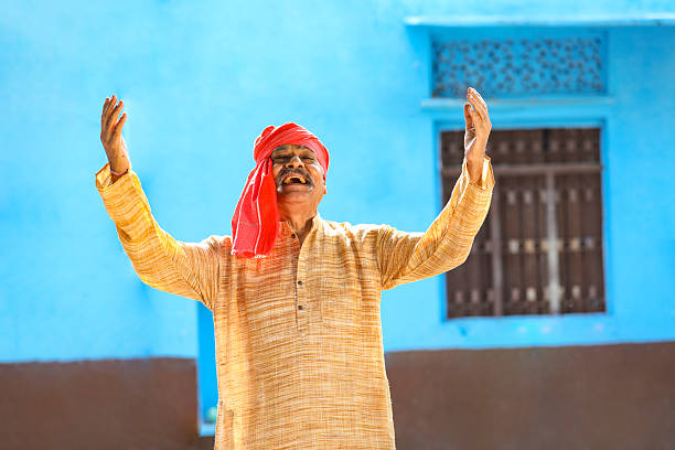 Old and senior indian farmer standing and giving happy expression