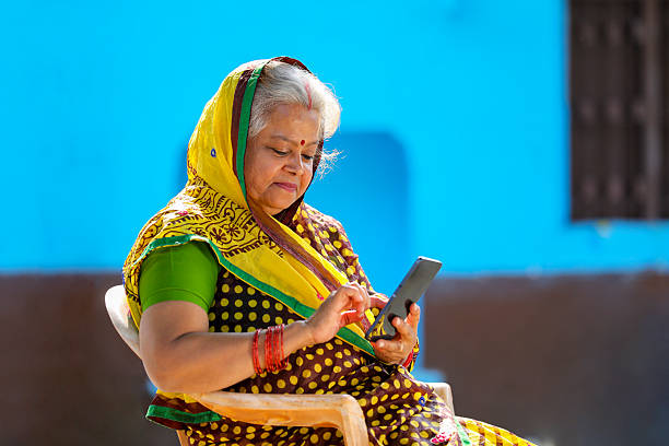 old Indian rural woman using smartphone at home