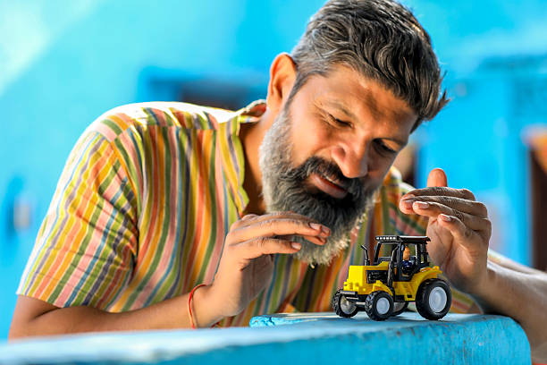 Indian farmer with tractor toy. vehicle loan concept