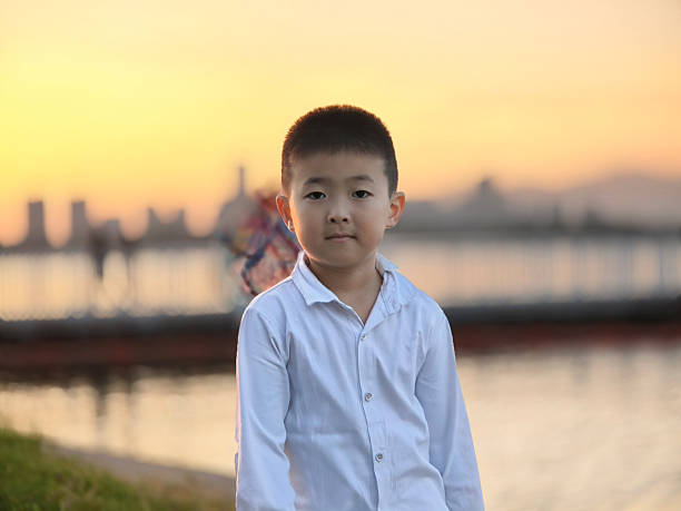 At sunset, the little boy got his tools ready and was going to scoop up the floating garbage on the water surface.