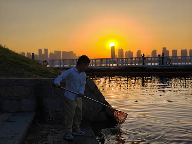 The little boy is carefully scooping up the garbage in the water