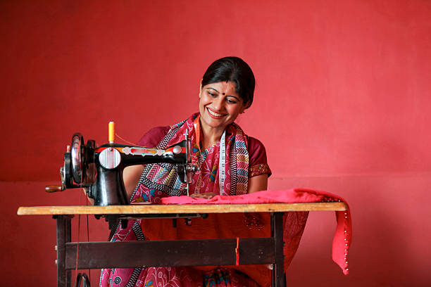 Indian rural woman using sewing machine at home