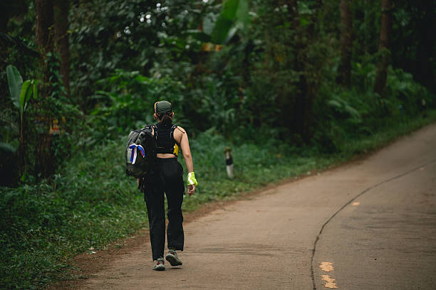 istock Young Woman Hiking Alone in Lush Green Forest Path with Backpack, Wearing Cap and Bright Gloves, Adventure and Nature Exploration Concept 2245931867