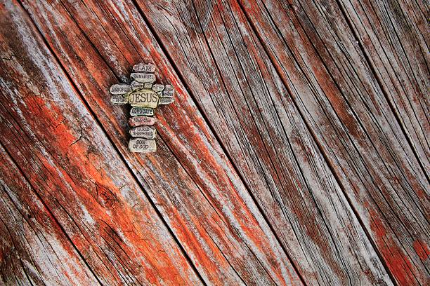 Stone cross on a reddish wooden texture background.