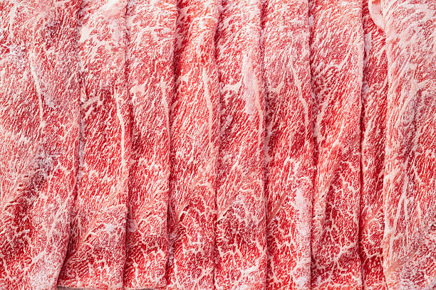 Close-up view of frozen marbled beef slices with visible fat pattern and icy surface