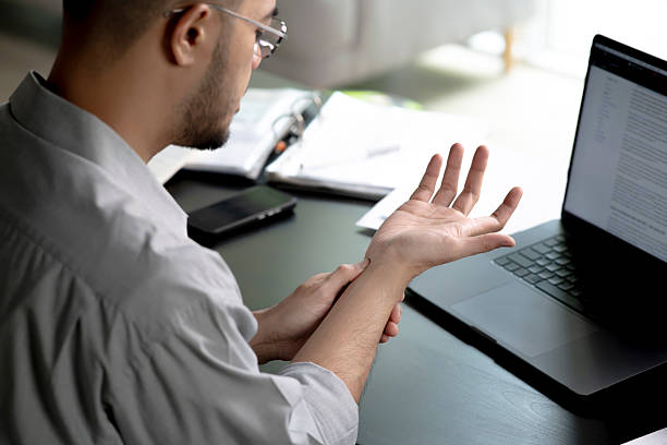 istock Businessman suffering from wrist pain while working on computer, Businessman massaging his hand and wrist after long hours in front of a computer 2245939412