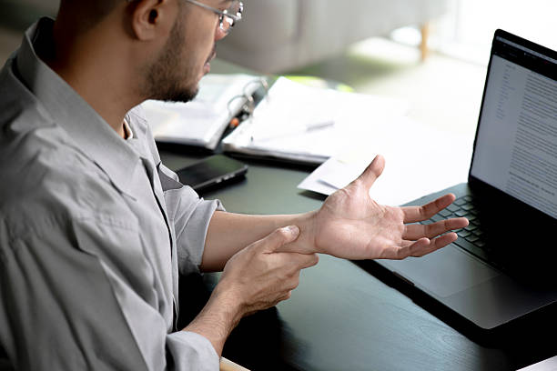 istock Businessman suffering from wrist pain while working on computer, Businessman massaging his hand and wrist after long hours in front of a computer 2245939413