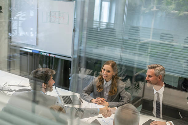 istock Businessmen shaking hands during a meeting, through a glass partition. 2245942932