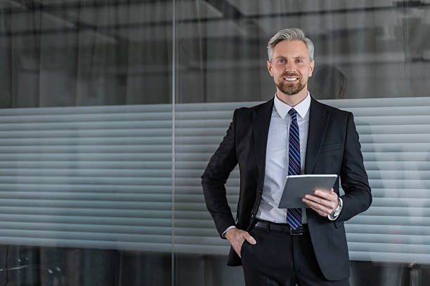 istock Smiling handsome businessman manager standing in office with tablet computer 2245943423