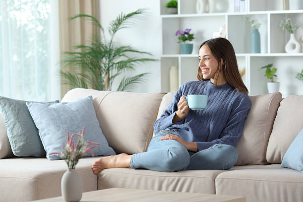 istock Happy woman in blue drinking coffee at home looking away 2245944930