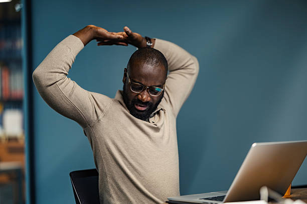 istock Black man stretching at office desk feeling tired 2245944985