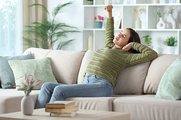 istock Woman in green stretching after nap on a couch 2245945016