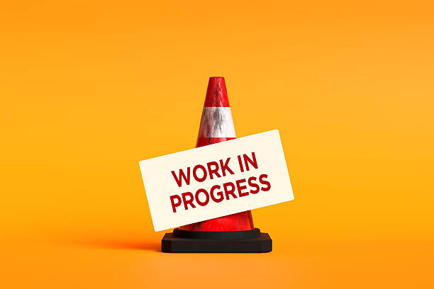 istock Work in progress sign on traffic cone against orange background 2245945281