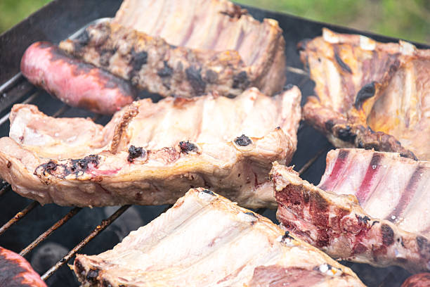 Close up of pork ribs and sausage grilling on a barbecue The Delicious Process of Outdoor Cooking