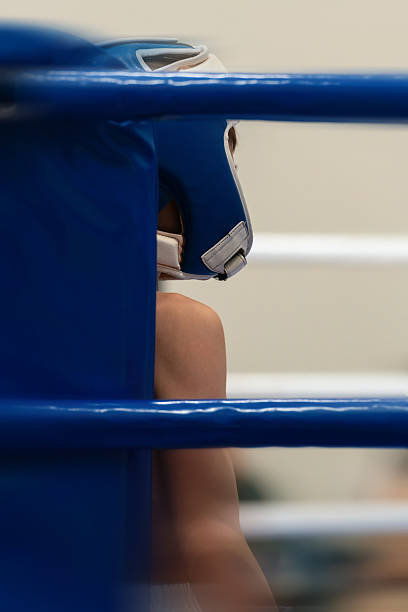 Boxing ring corner with partial view of fighter in blue gear. The composition includes motion blur and open space, allowing for text placement.