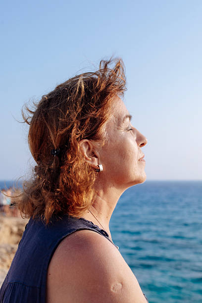 istock Smiling Woman Enjoying Ocean View at Sunset 2245950997