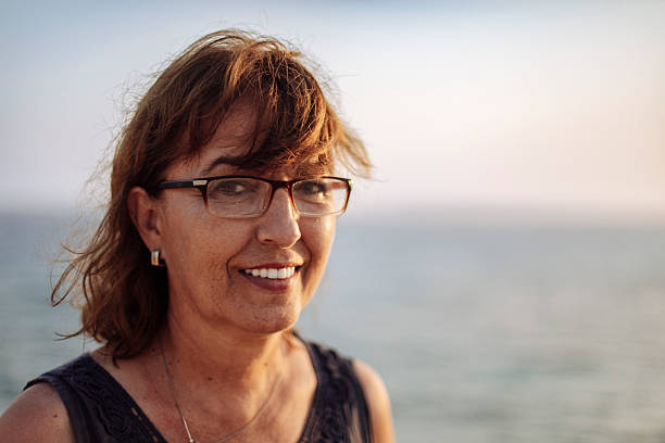 istock Smiling Woman Enjoying Ocean View at Sunset and looking at camera 2245951007