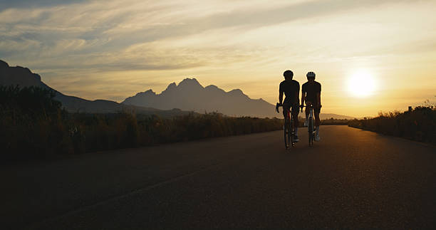 istock Sunset, workout and people with bicycle for exercise, countryside race or adventure trail together. Cycling, nature and friends with mountain bike for outdoor fitness, challenge and health training 2245952813