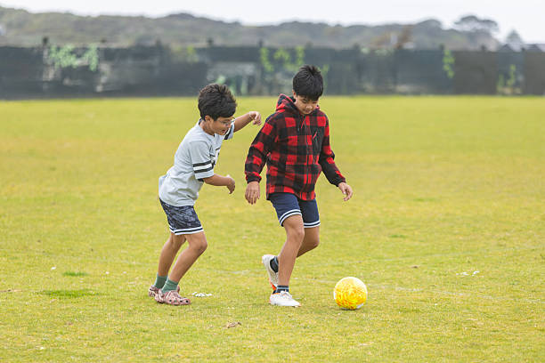 istock Brothers playing soccer in the park together 2245953622