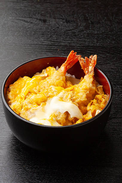 A bowl of rice topped with fried shrimp and soft scrambled eggs