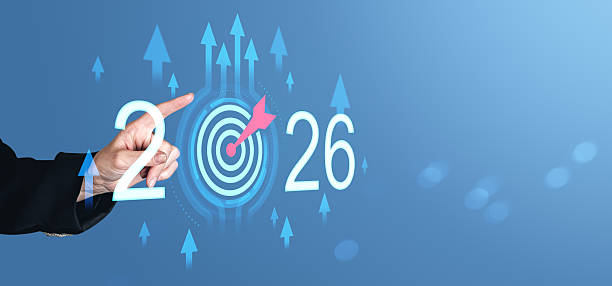 istock Hand pointing to digital target with arrow between glowing numbers 2026 and upward arrows on blue background symbolizing goal achievement concept. 2245958895