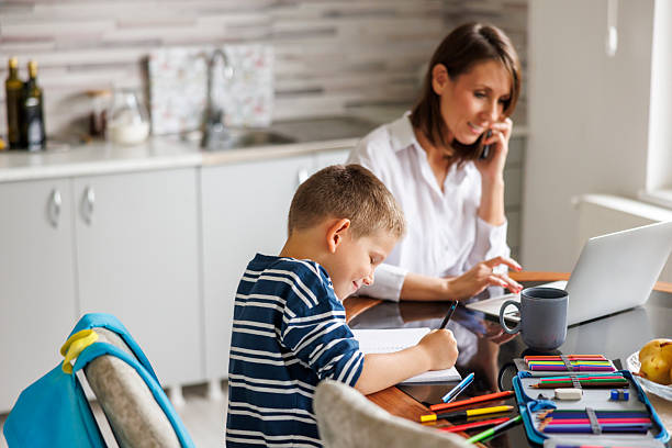 istock Mother having phone conversation and working while son doing homework at home 2245959409