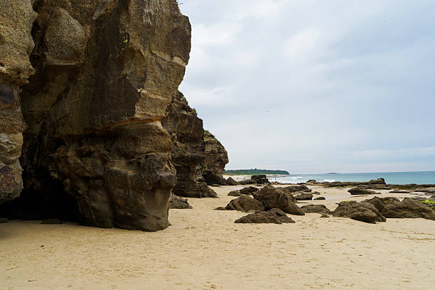 Low tide at Caves Beach reveals a dramatic landscape of sculpted rocks, reflective pools, and a vast sandy expanse leading to the sea caves