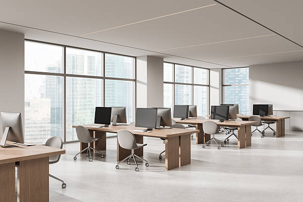 istock Modern open space office interior with wooden desks and computers in daylight with cityscape view through panoramic windows. 3D Rendering. 3D Rendering 2245960031