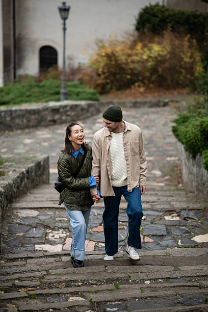 istock Diverse couple walking up stone stairs holding hands 2245960115
