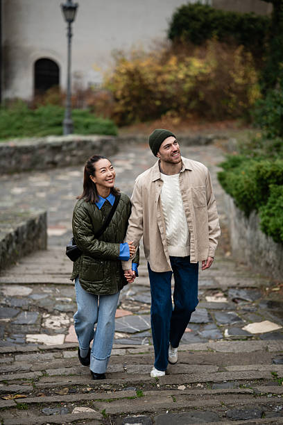 istock Happy couple holding hands walking up cobblestone stairs 2245960176