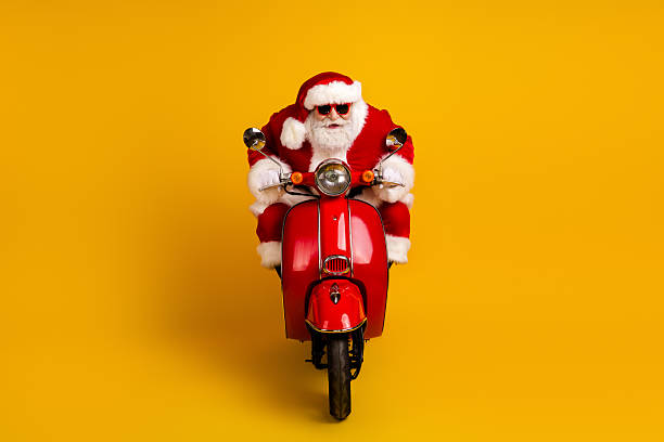 istock Santa rides a bright red scooter against a bold yellow background creating a playful festive image for Christmas season and holiday 2245966533
