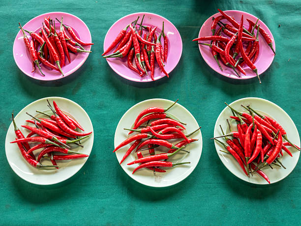 Close-up of fresh cabbage and chili peppers displayed in baskets at a local market stall.