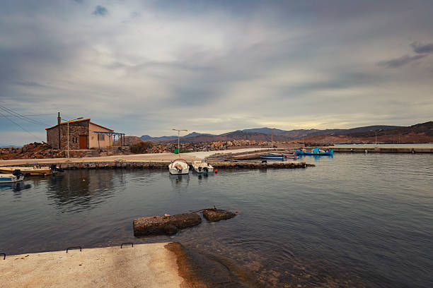 Coastal Harbor with Small Building and Boats Under Cloudy Sky