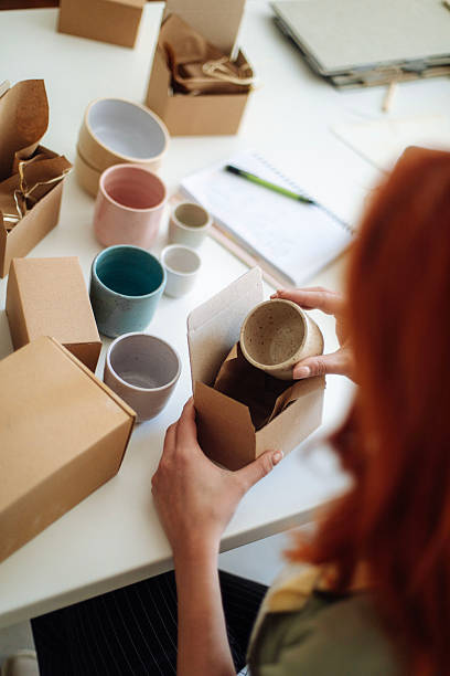istock female ceramic artist packing handmade mugs in studio 2245973806